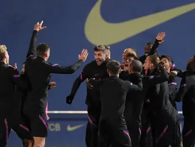 Bek Barcelona, Gerard Pique (tengah) merayakan dengan rekan satu timnya selama sesi latihan di stadion Camp Nou di Barcelona, Spanyol (22/11/2021). Barcelona akan bertanding melawan Benfica pada Grup E Liga Champions di Camp Nou. (AFP/Gen Lluis)