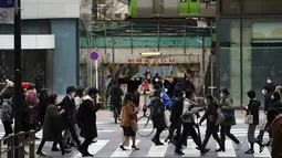 Orang-orang yang mengenakan masker berjalan di sepanjang penyeberangan pejalan kaki di daerah Shibuya, Tokyo, Selasa (5/1/2021). Pemerintah Jepang sedang mempertimbangkan mendeklarasikan keadaan darurat untuk Tokyo karena kasus infeksi virus corona yang terus meningkat. (AP Photo/Eugene Hoshiko)