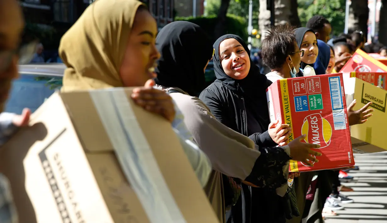 Relawan membagikan baju dan barang lainnya pada korban kebakaran apartemen Grenfell Tower di Kensington, London, (15/6). Apartemen tersebut diketahui baru saja direnovasi yang menghabiskan biaya 8,7 juta poundsterling. (AP Photo/Alastair Grant)