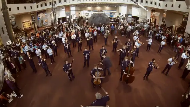 Para pemusik Angkatan Udara AS menyeruak di antara pengunjung dan mulai bermain ensembel secara ‘flash mob’.