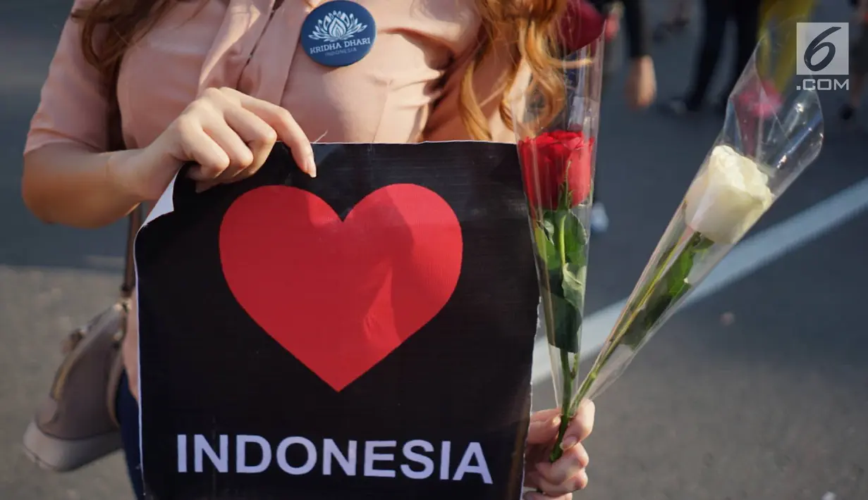 Relawan memegang bunga mawar untuk dibagikan ke pengunjung car free day di kawasan Bundaran HI, Jakarta, Minggu (30/6/2019).  Aksi 1000 bunga mawar itu sebagai bentuk rasa syukur atas kemenangan pasangan Jokowi-Ma'ruf Amin di Pilpres 2019. (Liputan6.com/Immanuel Antonius)