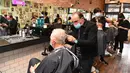 Para pria memotong rambut di barber shop di Melbourne, Australia, Senin (19/10/2020). Warga Kota Melbourne, pada Senin (19/10), akhirnya bisa bernafas lega saat sejumlah pembatasan dilonggarkan setelah menjalani lockdown tahap keempat yang ketat selama sekitar 100 hari. (William WEST/AFP)