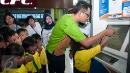 Petugas KAI menunjukan cara memesan tiket kepada murid PAUD di Stasiun Gambir, Jakarta, Senin (20/3). PT KAI mengajak anak Indonesia untuk mengenal lebih jauh tentang kereta api sekaligus memperingati hari dongeng sedunia. (Liputan6.com/Gempur M Surya)