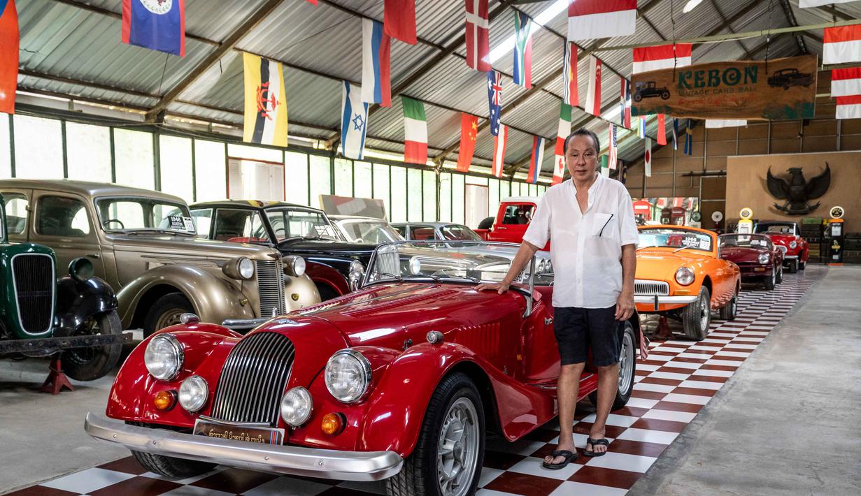 Foto yang diambil pada 14 Oktober 2025 ini menunjukkan Jos Dharmawan, pengusaha dan pendiri Museum Mobil Antik Kebon, berpose di samping Morgan Plus 8 tahun 1990 di antara koleksi mobil klasiknya di museumnya di Bali. Inilah garasi impian Jos Dharmawan, seorang kolektor yang telah menyulap ruang privatnya menjadi sebuah museum hidup, untuk ratusan mobil klasik dan antik. (Dicky Bisinglasi/AFP)
