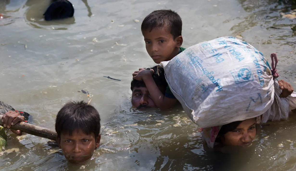 Sebuah keluarga dari etnis Rohingya melintasi sungai Naf untuk mencapai perbatasan Bangladesh di daerah Teknaf Cox's Bazar (5/9). Mereka berusaha melarikan diri ke Bangladesh, sejak bentrokan kembali pecah di Rakhine.(AP Photo/Bernat Armangue)