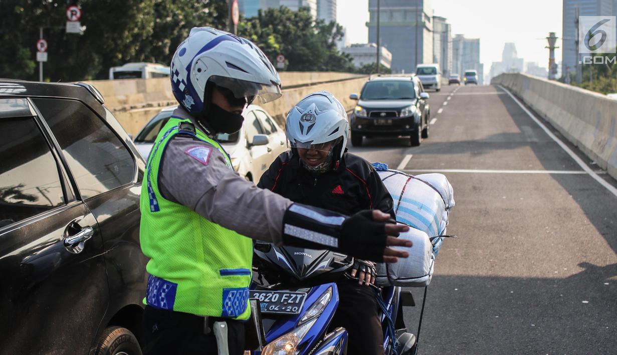 Petugas kepolisian memberhentikan pengemudi sepeda motor yang melintasi JLNT Kampung Melayu-Tanah Abang, Jakarta, Selasa (25/7). Polisi terus merazia kendaraan roda dua yang melanggar rambu larangan melintas di JLNT tersebut. (Liputan6.com/Faizal Fanani)