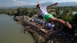 Penonton menyaksikan dari tepi sungai saat seorang peserta melakukan terjun bebas dari jembatan Ura e Shejnt dalam kompetisi menyelam tradisional ke-68 di Gjakova, Kosovo, 22 Juli 2018. Kompetisi ini dilakukan dari ketinggian 22 meter. (AP/Visar Kryeziu)