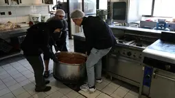 Gelombang pengungsian ini terjadi setelah peringatan evakuasi dan serangan udara intensif di wilayah selatan dan Beirut. Tampak dalam foto, para sukarelawan memasak makanan untuk para pengungsi yang menghindari serangan udara Israel di Lebanon selatan dan Dahiyeh, di Institut Teknik Bir Hassan yang telah diubah menjadi tempat penampungan, Beirut, Rabu 11 Maret 2026. (AP Photo/Bilal Hussein)