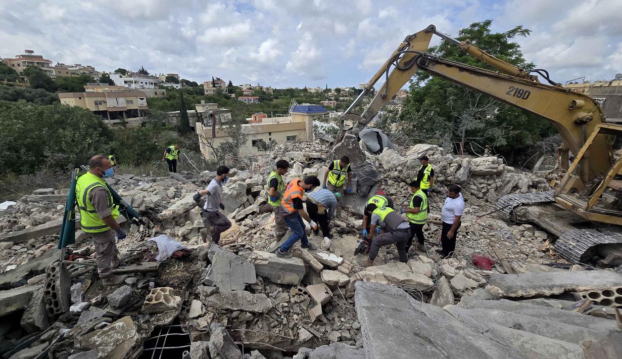 Para pekerja pertahanan sipil Lebanon menyisir reruntuhan, sehari setelah serangan Israel di desa Deir Qanun al-Nahr, Lebanon Selatan, pada Rabu 20 Mei 2026. (KAWNAT HAJU/AFP)