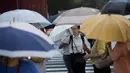 Pejalan kaki menggunakan payung berjalan saat hujan turun di Tokyo, Jepang (8/8). Topan kuat sedang mengarah ke Jepang pada 8 Agustus, mendorong badan cuaca untuk memperingatkan akan terjadi hujan lebat dan angin kencang. (AFP Photo/Behrouz)