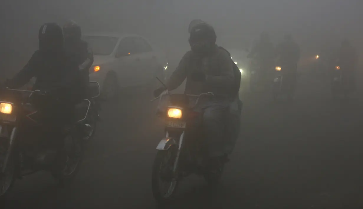 Kendaraan melaju dengan menyalakan lampu depan saat kabut tebal menyelimuti Lahore, Pakistan, 15 Desember 2021. Kabut tebal membuat kendaraan harus melaju lambat karena jarak pandang berkurang. (AP Photo/K.M. Chaudary)