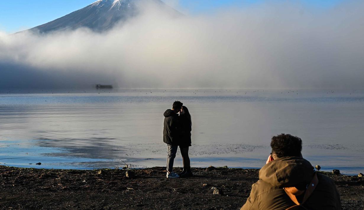 Dengan pesonanya yang menawan, berpadu dengan nilai budaya dan spiritual, menjadikan Gunung Fuji sebagai tempat yang wajib dikunjungi ketika berlibur ke Negeri Sakura. Tampak dalam foto, para wisatawan berpose di depan Gunung Fuji, gunung tertinggi di Jepang dengan ketinggian 3.776 meter (12.460 kaki), di kota Fujikawaguchiko, Prefektur Yamanashi, pada Senin 17 November 2025 pagi hari. (Caroline GARDIN/AFP)