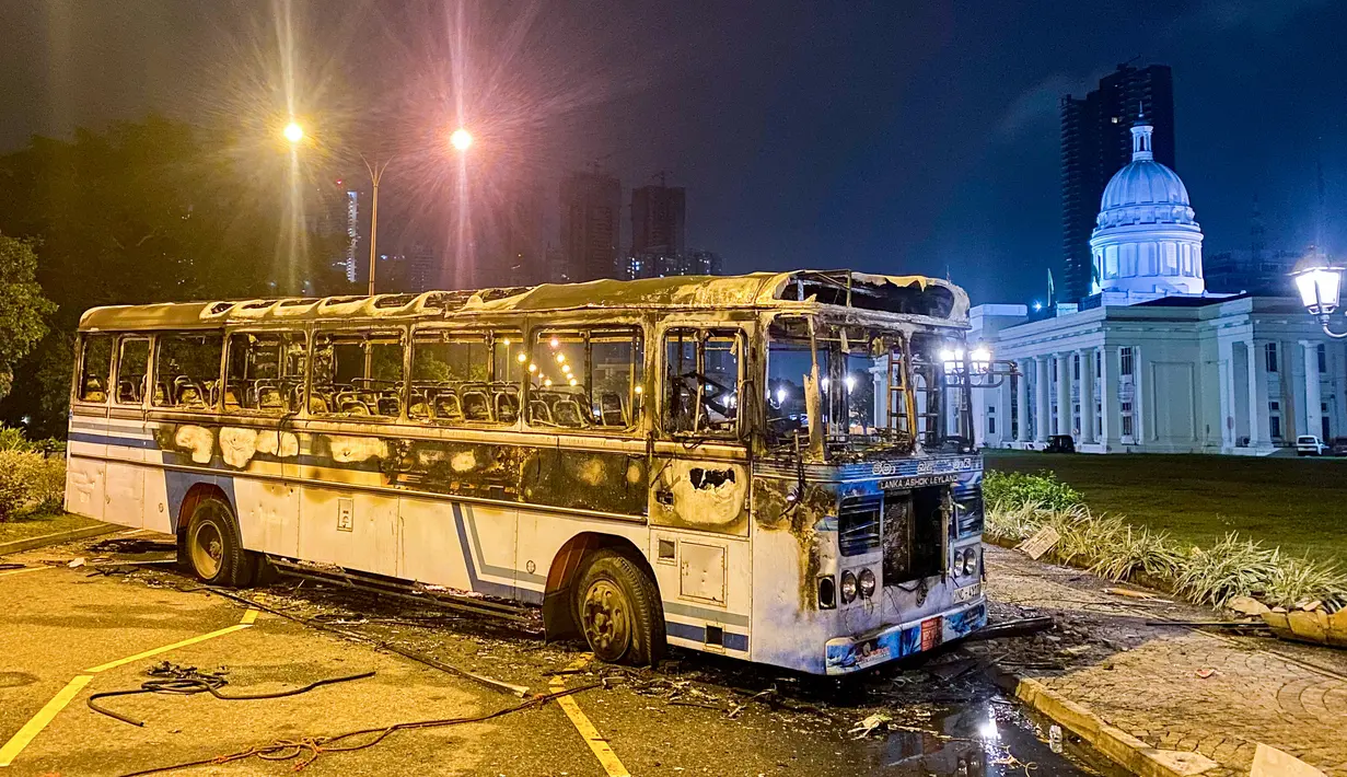 <p>Sisa-sisa bus yang hangus terlihat di dekat kediaman resmi Perdana Menteri Sri Lanka Mahinda Rajapaksa di Kolombo 9 Mei 2022. Puluhan bus yang digunakan oleh loyalis Rajapaksa untuk melakukan perjalanan ke Kolombo pada hari sebelumnya dibakar atau rusak di seluruh negeri. (ISHARA S. KODIKARA / AFP)</p>