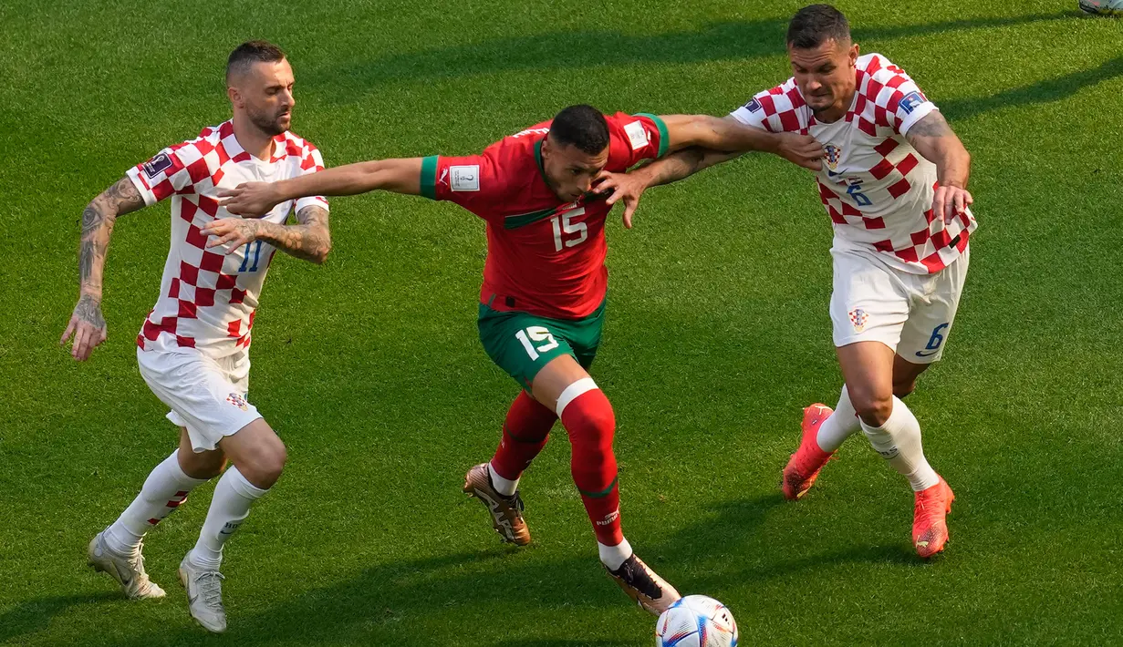 Pemain Kroasia Marcelo Brozovic (kiri) dan Dejan Lovren (kanan) berebut bola dengan pemain Maroko  Selim Amallah (tengah) pada pertandingan sepak bola Grup F Piala Dunia 2022 di Stadion Al Bayt, Al Khor, Qatar, Rabu (23/11/2022). Pertandingan berakhir imbang dengan skor 0-0. (AP Photo/Darko Vojinovic)