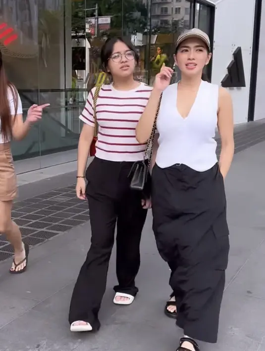 Angel Karamoy juga mengajak putrinya liburan ke Singapura. Nampak Angel mengenakan atasan vest putih dipadukan rok hitam panjangnya. @realangelakaramoy