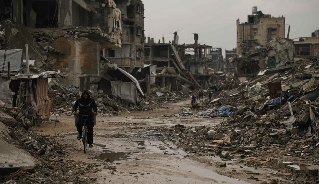Otoritas kesehatan Gaza menggambarkan situasi ini sebagai tragedi keempat yang menimpa warga di Gaza, selain pembunuhan, pengungsian, dan terusir tanpa masa depan. Tampak dalam foto, seorang pria Palestina mengendarai sepedanya melewati reruntuhan di tengah cuaca buruk Kota Gaza, Kamis 11 Desember 2025. (AP Photo/Jehad Alshrafi)