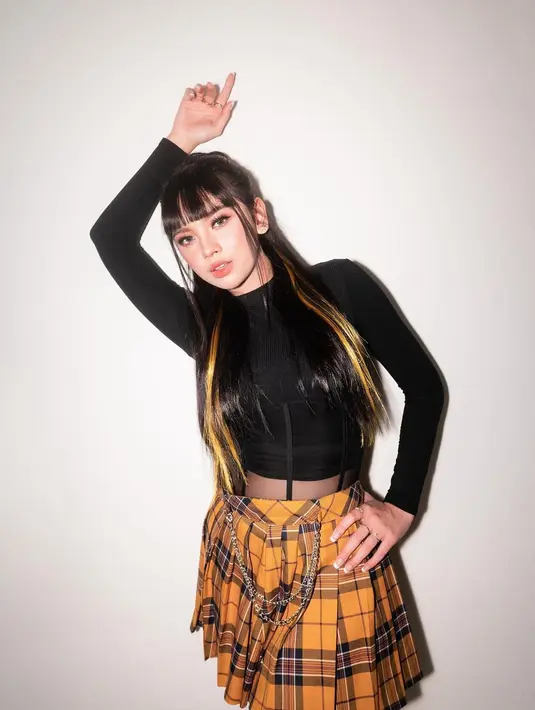 Mengenakan long sleeve berwarna hitam yang dipadukan dengan tartan skirt berwarna kuning. [instagram/lyodraofficial]