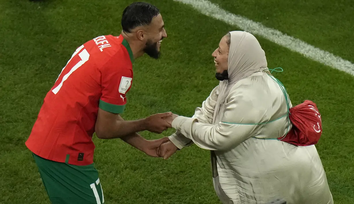 Gelandang Maroko #17 Sofiane Boufal merayakan bersama ibunya setelah lolos ke semifinal dengan mengalahkan Portugal pada babak 8 besar Piala Dunia 2022 di Stadion Al-Thumama di Doha, Sabtu (10/12/2022). Tarian Boufal dengan ibunya di pinggir lapangan Stadion Al Thumama setelah pertandingan viral di media sosial. (AP Photo/Alessandra Tarantino)
