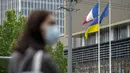 Seseorang yang memakai masker menunggu untuk melintasi persimpangan saat bendera Prancis, Ukraina, dan Uni Eropa berkibar di Kedutaan Besar Prancis di Beijing, China, Rabu (17/5/2023). (AP Photo/Mark Schiefelbein)