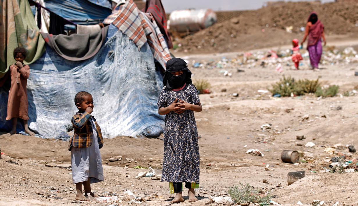Sejumlah anak-anak Yaman berdiri dekat tenda pengungsian di kamp pengungsian di Sanaa, Yaman (15/4). WHO mencatat sebanyak 2,1 juta orang telah terlantar akibat konflik yang terjadi di Yaman. (AFP Photo / Mohammed Huwais)