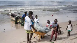 Anak-anak di lingkungan sekitar bergabung dengan relawan untuk membersihkan pantai di pinggiran Dakar, Senegal (13/9/2020). Relawan dan penduduk setempat berpartisipasi dalam kegiatan bersih-bersih pantai di Thiaroye-sur-Mer, sebuah kota kecil di pinggiran Dakar. (Xinhua/Louis Denga)