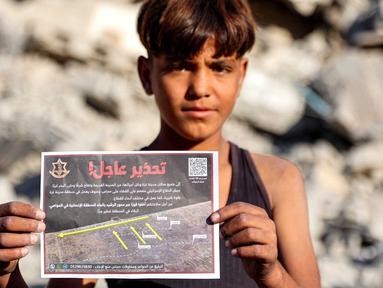 Seorang anak laki-laki memegang salah satu selebaran yang dijatuhkan oleh militer Israel di Kota Gaza, yang menyerukan evakuasi ke selatan menuju al-Mawasi, pada 9 September 2025. (Omar AL-QATTAA/AFP)