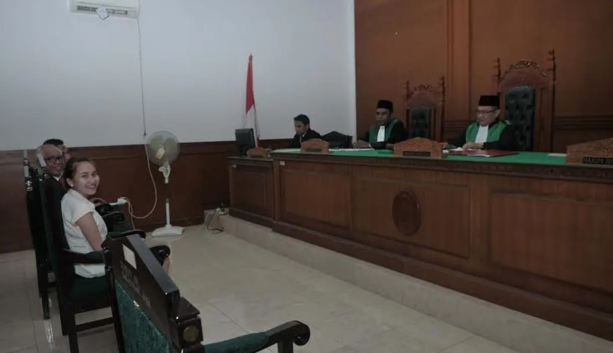  Hingga berada dalam ruang sidang pun, Ayu tetap tersenyum bahkan tetap bersikap ceria. Sidang Ayu Ting Ting terpaksa ditunda karena Enji tidak hadir (Liputan6.com/Rini Suhartini)