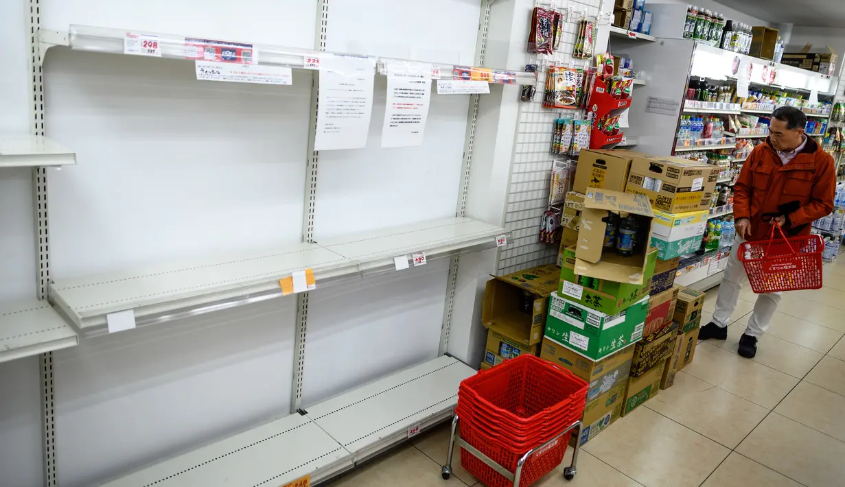 Seorang pria berbelanja di rak supermarket kosong yang biasanya penuh dengan tisu toilet di Tokyo, Minggu (1/3/2020). Warga Jepang yang sedang waspada wabah virus corona tipe baru, Covid-19 dilanda kepanikan setelah muncul gosip bahwa China tidak akan lagi mengekspor kertas toilet. (Philip FONG/AFP)