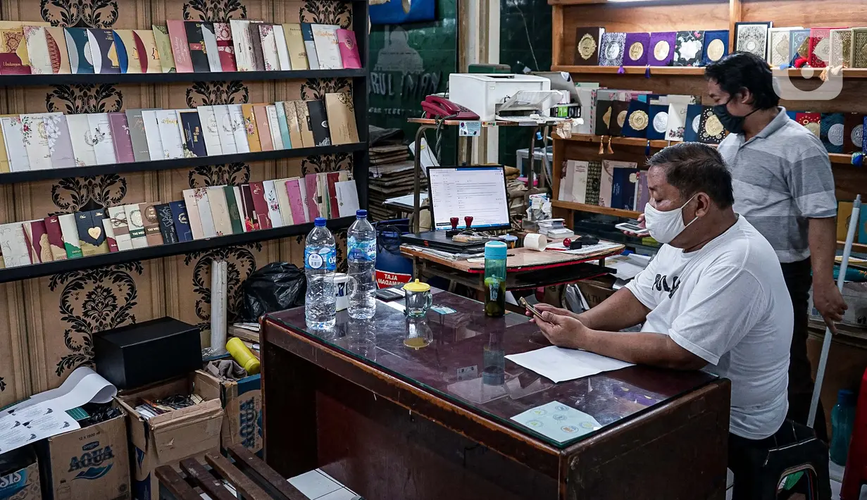 Aktivitas pedagang kertas undangan pernikahan di Pasar Tebet, Jakarta, Kamis (22/7/2020). Adanya larangan saat pandemi covid-19 untuk mengadakan acara yang bisa menimbulkan kerumunan, seperti pesta pernikahan, menyebabkan pendapatan usaha percetakan ini turun drastis. (Liputan6.com/Faizal Fanani)