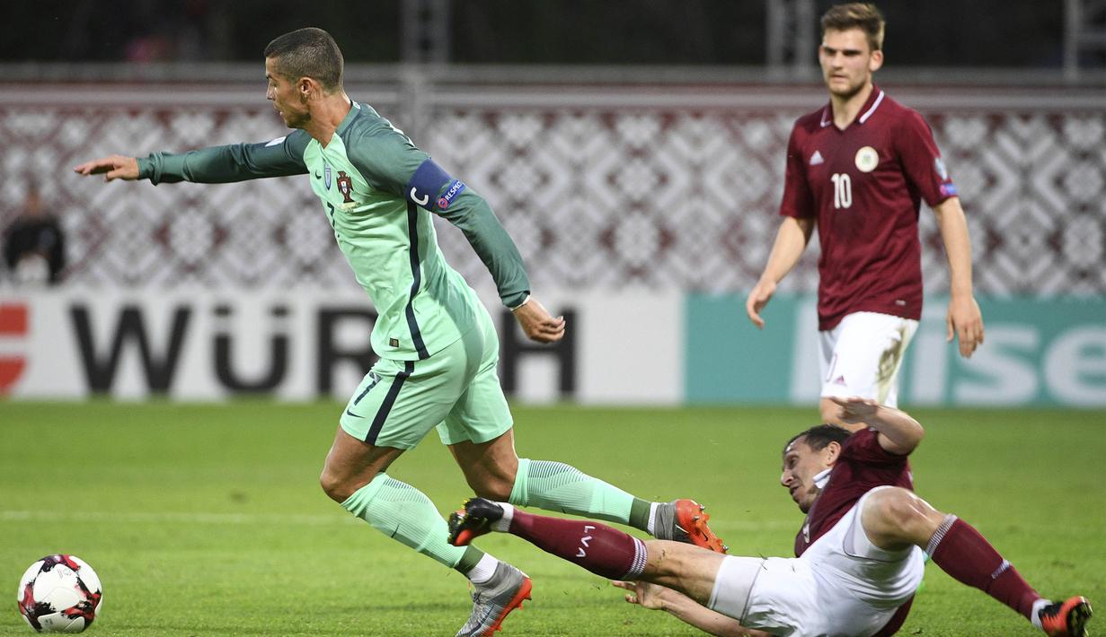 Bintang Portugal, Cristiano Ronaldo, menghindari tekel bek Latvia, Olegs Laizns, pada laga kualifikasi Piala Dunia 2018 di Stadion Skonto, Riga, Jumat (9/6/2017). Latvia kalah 0-3 dari Portugal. (AP/Roman Koksarov)