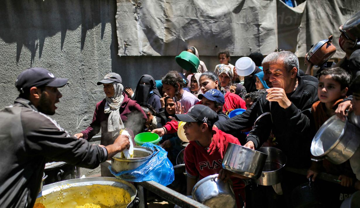 Mengutip data dari Kantor Koordinasi Urusan Kemanusiaan (OCHA), Juru Bicara PBB Stephane Dujarric, menyatakan ada sekitar 2,1 juta orang di Gaza kini terkurung di kurang dari setengah wilayahnya. Tampak dalam foto, orang-orang berebut untuk mendapatkan makanan hangat di kamp pengungsi Palestina, Nuseirat, Jalur Gaza Tengah pada Kamis 7 Mei 2026. (Eyad Baba/AFP)