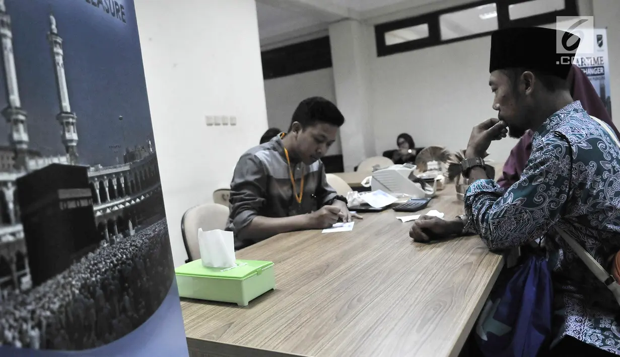 Petugas melayani calon jemaah haji yang menukarkan mata uang rupiah ke riyal di Asrama Haji Pondok Gede, Jakarta, Senin (22/7/2019). Embarkasi Haji Pondok Gede menyediakan empat titik pelayanan penukaran pecahan mata uang rupiah ke riyal. (merdeka.com/Iqbal Nugroho)