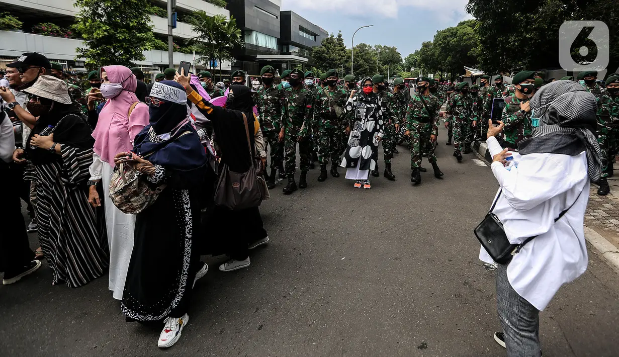 Prajurit TNI menghalau massa yang hendak menggelar demonstrasi 1812 di sekitar Istana Negara, Jakarta, Jumat (18/12/2020). Demo bertajuk Aksi 1812 ini selain menuntut pembebasan Rizieq Shihab, juga mendesak pengusutan kasus enam anggota FPI yang tewas tertembak polisi. (Liputan6.com/Johan Tallo)