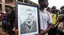 Seorang penduduk setempat memegang potret pemain Paris Saint-Germain sekaligus kapten Timnas Prancis, Kylian Mbappe yang mengunjungi sekolah umum dwibahasa Bonendale, yang direnovasi oleh yayasan Inspired By Kylian Mbappe Foundation (IBKM), di Douala pada 8 Juli 2023. (AFP/Daniel Beloumou Olomo)