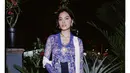Eva Celia tampil elegan dan glamor dalam balutan kebaya kutubaru bertekstur berwarna biru yang dipadukan dengan selendang putih dan kain batik bernuansa putih. Bros besar emas yang disematkan di dada menambah kemewahan penampilannya. [@evacelia]