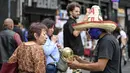 Seorang pedagang kaki lima yang mengenakan topeng gulat tradisional Meksiko menunjukkan suvenir berbentuk piala Piala Dunia kepada pejalan kaki di Mexico City, Senin 8 Juni 2026. (Yuri CORTEZ/AFP)