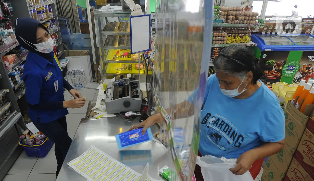 Pekerja melayani pembeli dari balik plastik pembatas pada sebuah minimarket di kawasan Cinere, Depok, Jawa Barat, Rabu (8/4/2020). Penggunaan plastik pembatas tersebut bertujuan untuk mengantisipasi penyebaran virus corona atau COVID-19 sebagai bentuk social distancing. (merdeka.com/Arie Basuki)