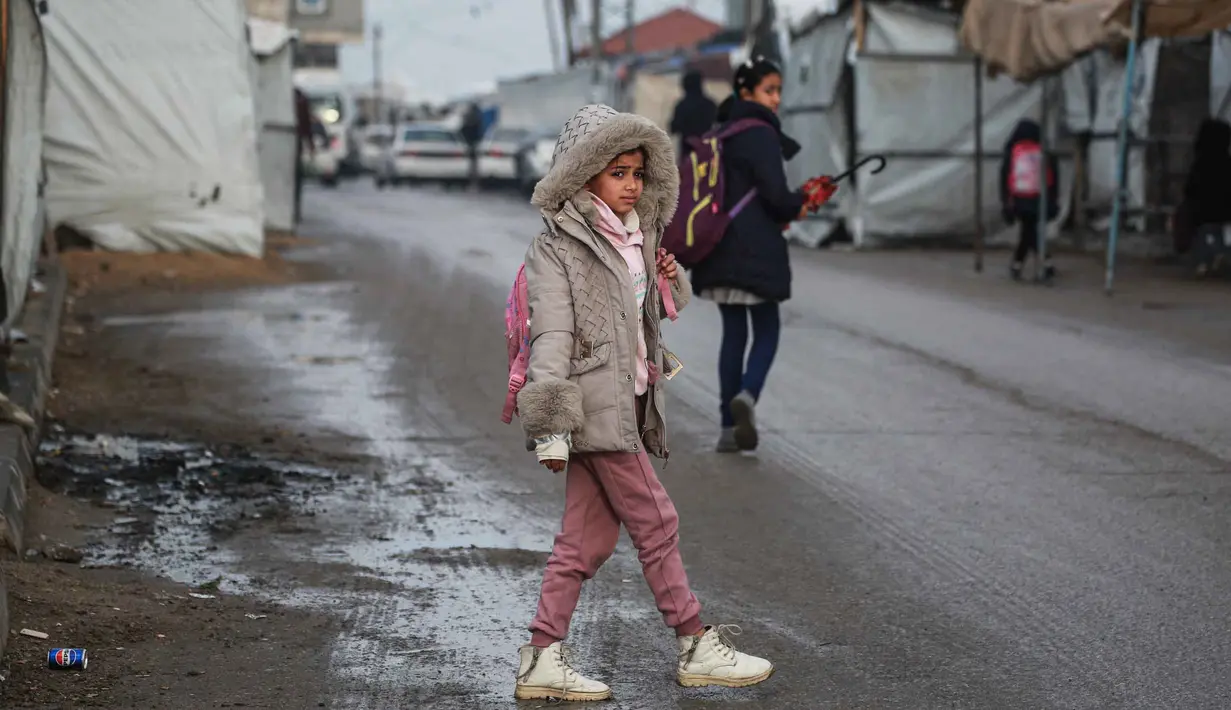 Seorang gadis kecil berjalan menuju sekolah di Deir al-Balah, di Jalur Gaza tengah, pada 10 Desember 2025. Secara bertahap, anak-anak di Gaza mulai kembali ke sekolah. (BASHAR TALEB/AFP)