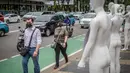 Pejalan kaki melintas di depan manekin yang dipajang dalam aksi di Polda Metro Jaya, Senin (21/3/2022). Aksi tersebut bentuk dukungan terhadap Haris Azhar dan Fatia Maulidiyanti saat menjalani pemeriksaan terkait kasus dugaan pencemaran nama baik Luhut Binsar Pandjaitan. (Liputan6.com/Faizal Fanani)