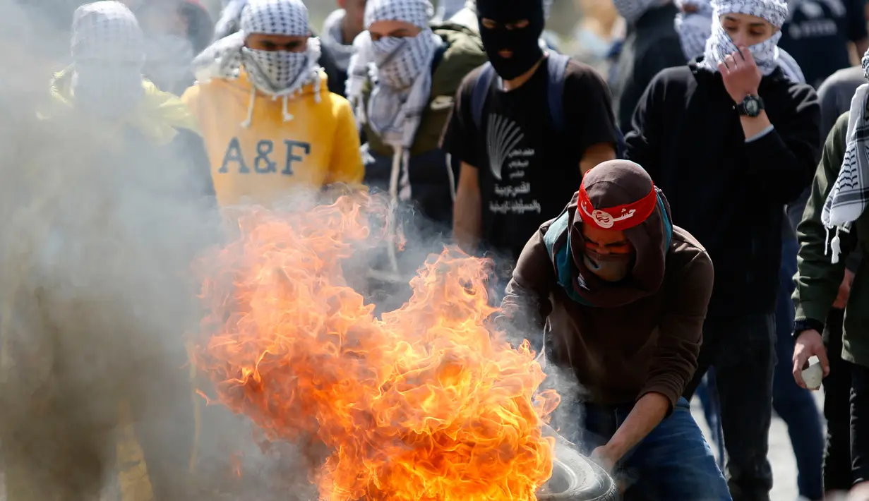 Pengunjuk rasa Palestina membakar ban saat bentrokan dengan pasukan Israel di pinggiran Kota Ramallah, Tepi Barat, Rabu (27/3). Bentrokan ini sebagai bentuk protes terhadap tahanan Palestina yang berada di Israel. (AP Photo/Majdi Mohammed)