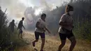Orang-orang berlari untuk menyelamatkan diri dari api kebakaran hutan di dekat desa Melon, Spanyol barat laut, pada 17 Agustus 2025. (MIGUEL RIOPA/AFP)