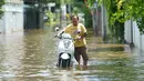 Seorang pria mendorong sepeda motor di sebuah jalan yang terendam banjir pascahujan lebat di Bangkok, Thailand (31/8/2020). (Xinhua/Rachen Sageamsak)