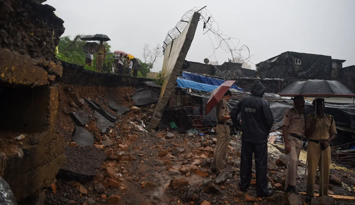 Polisi dan petugas penyelamat mengecek lokasi runtuhnya tembok di Mumbai, India (2/7/2019). Tragedi tersebut terjadi ketika pemukiman pantai yang dipenuhi 20 juta penduduk dihantam hujan lebat selama dua hari berturut-turut, membuat kota terhenti total. (AFP Photo/Punit Paranjpe)