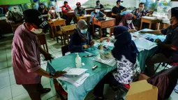 Suasana pencairan bantuan sosial tunai (BST) terhadap warga penerima manfaat di SDN Kembangan Utara 05 Pagi, Jakarta, Rabu (31/3/2021). Program BST sebesar Rp300 ribu dari Kemensos ini disalurkan melalui RT-RT se kelurahan Kembangan Utara melalui ATM Bank DKI. (Liputan6.com/Johan Tallo)