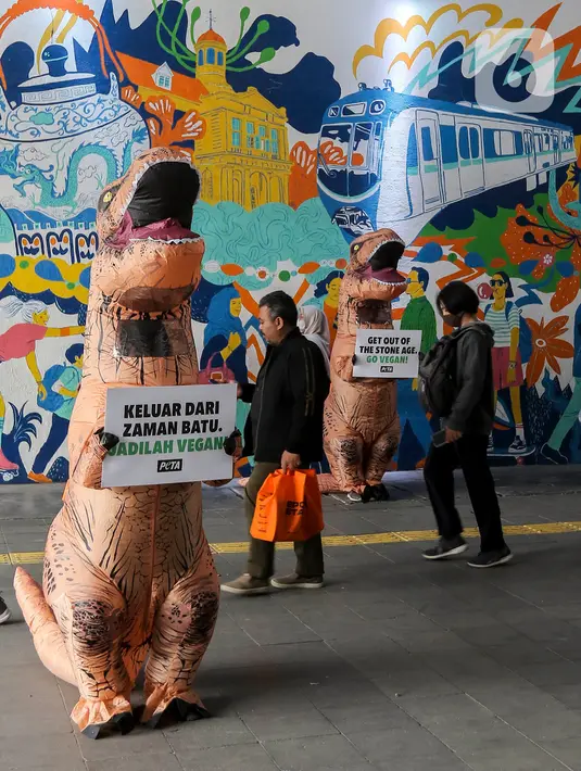 Sejumlah aktivis dari People for the Ethical Treatment of Animals (PETA) menggunakan kostum dinosaurus sambil membawa poster di kawasan Dukuh Atas, Jakarta, Selasa (24/10/2023). (Liputan6.com/Angga Yuniar)