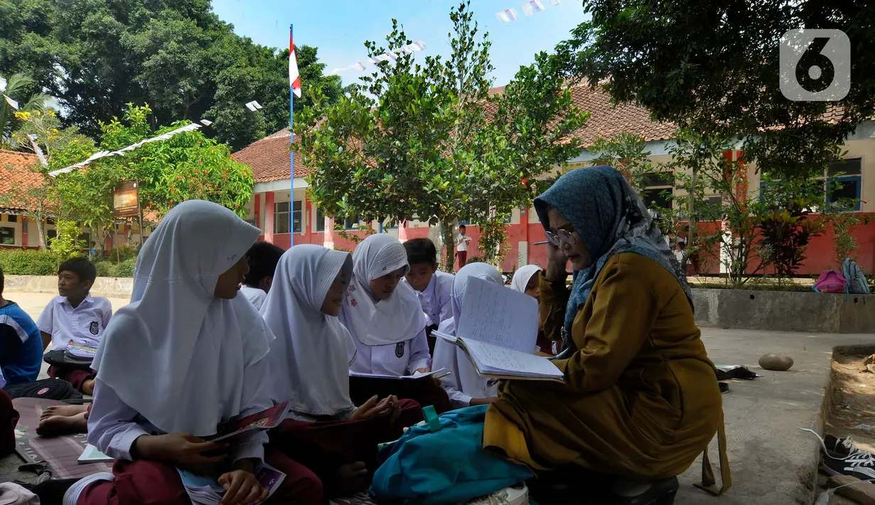 Guru saat mengajar di halaman sekolah di SDN Sukagalih, Kampung Benda, Desa Mekargalih, Kecamatan Cikalong Kulon, Cianjur Senin (29/8/2022). Akibat tiga ruangan kelas rusak berat dan terancam ambruk, sejumlah murid terpaksa belajar di halaman dan musholla sejak awal pembelajaran tatap muka Juli kemarin. (merdeka.com/Arie Basuki)