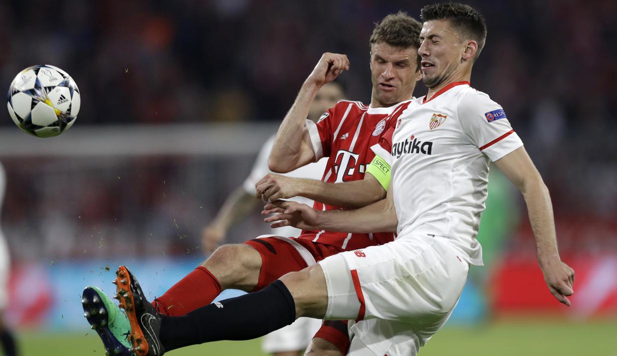 Pemain Bayern, Thomas Mueller (kiri) berebut bola dengan pemain Sevilla, Clement Lenglet pada leg kedua perempat final Liga Champions di Allianz Arena stadium, Munich, (11/4/2018). Bayern lolos ke semifinal dengan agregat 2-1. (AP/Matthias Schrader)