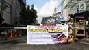 Warga melintasi portal yang terpasang spanduk pembatasan aktivitas di pintu masuk perumahan, Cideng, Jakarta, Kamis (2/4/2020). Pemerintah menetapkan Pembatasan Sosial Berskala Besar dengan membatasi kegiatan tertentu di wilayah yang diduga terinfeksi COVID-19. (Liputan6.com/Helmi Fithriansyah)