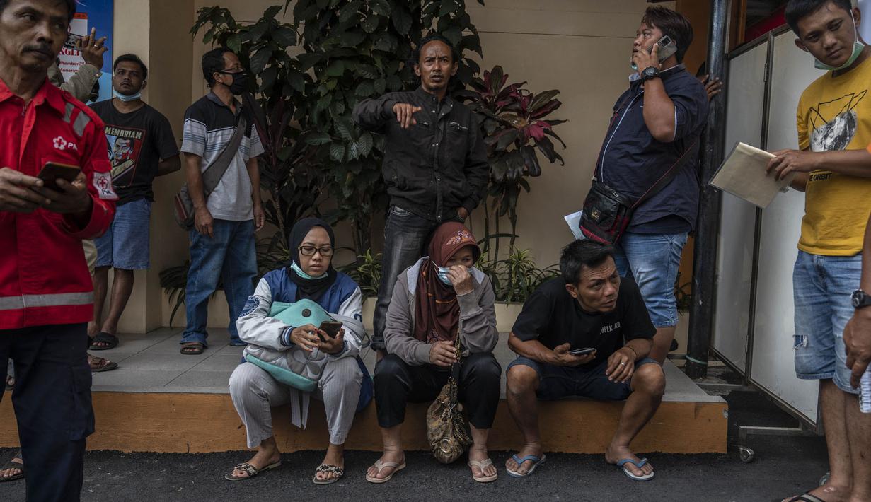 Keluarga dan kerabat korban tragedi Stadion Kanjuruhan menunggu di luar sebuah rumah sakit di Malang, Jawa Timur pada 2 Oktober 2022. Sedikitnya 174 orang tewas di stadion sepak bola Indonesia ketika ribuan penggemar tuan rumah yang marah menyerbu lapangan dan polisi menanggapi dengan gas air mata yang memicu desak-desakan, kata pihak berwenang pada 2 Oktober. (AFP/Juni Kriswanto)