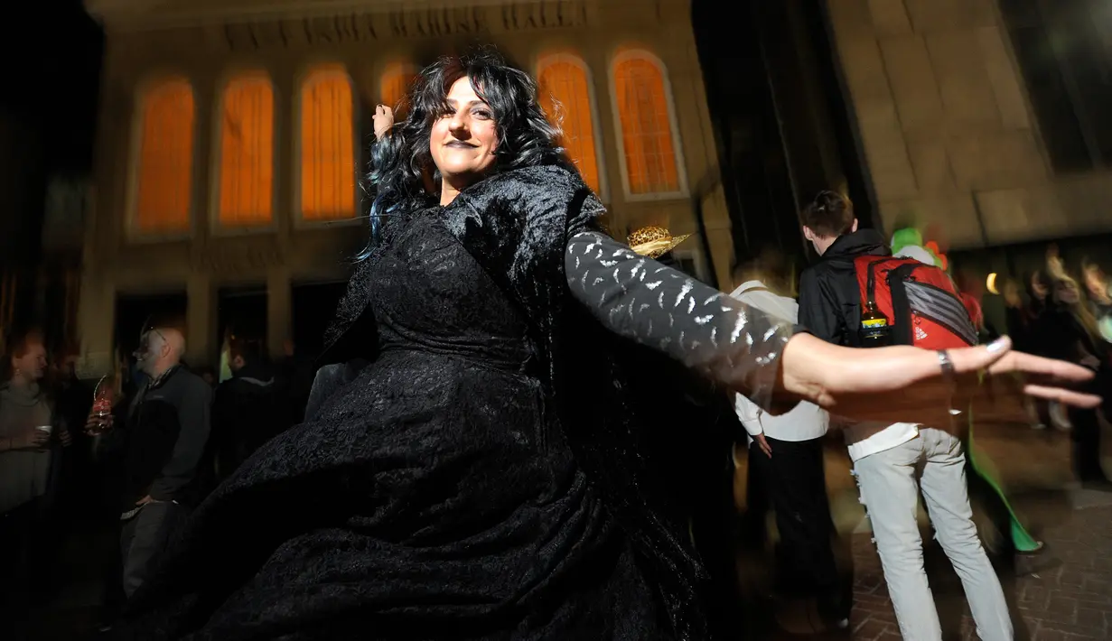 Seorang wanita mengenakan kostum sambil menari saat perayaan Halloween di jalanan kota Salem, Massachusetts, AS, Rabu (31/10). Kota Salem juga dikenal sebagai Kota Penyihir karena memiliki banyak tempat yang menyeramkan. (Joseph PREZIOSO/AFP)
